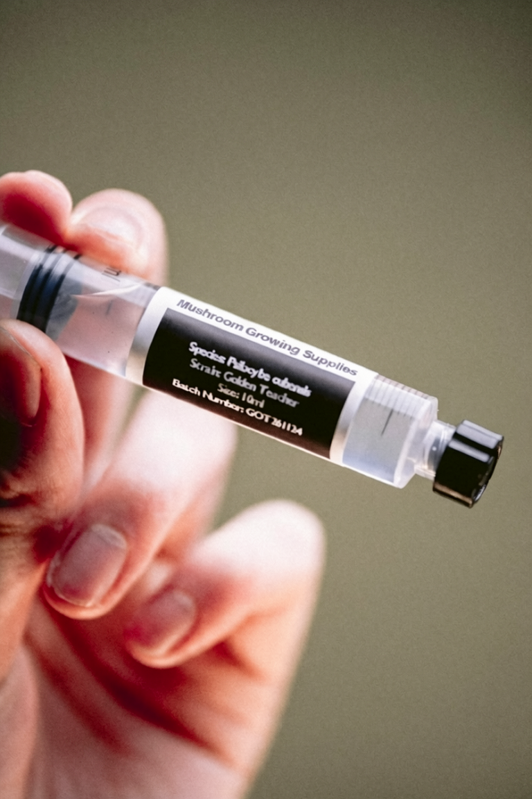 An image depicting a hand holding a microscopy spore syringe.